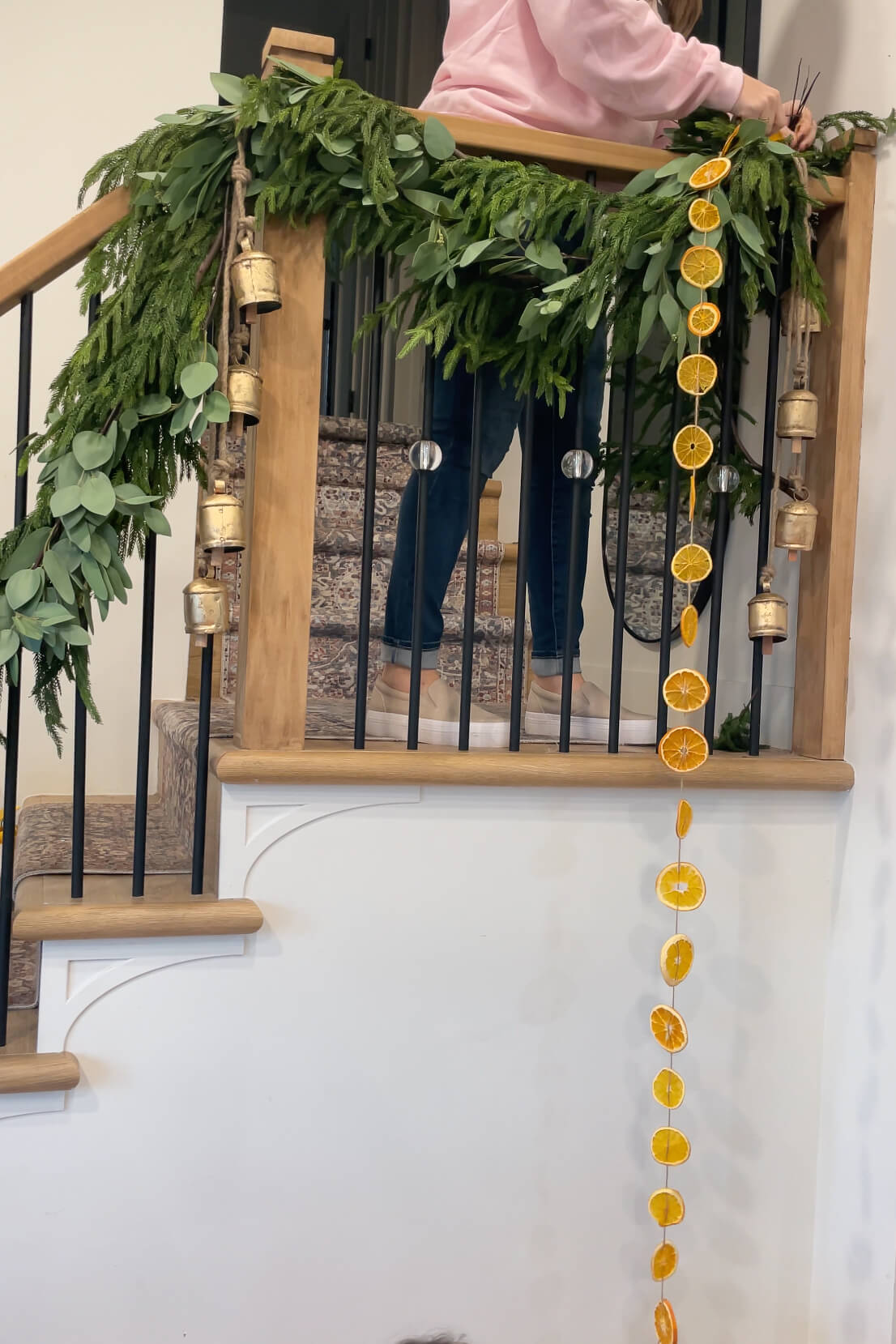 Adding an orange slice garland to a staircase for Christmas decorations.